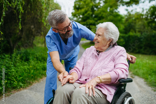 Male home nurse taking care of elderly woman in wheelchair.
