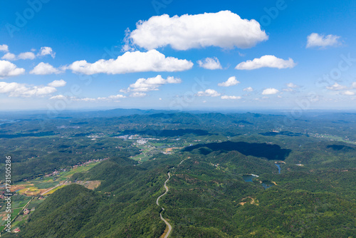 Dahong Mountain rises majestically under a blue sky with white clouds, showcasing lush green landscapes and rolling hills stretching across Suizhou, China.