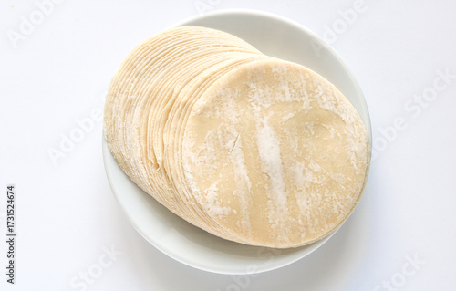 A stack of round and thinly dumpling wrappers or skins, lightly dusted with flour and ready for use. These versatile dough creates a variety of dishes such as dumplings, gyozas, and wonton. 