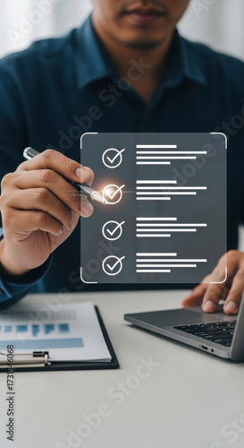 Close-up of person using digital checklist interface with laptop. Professional office setting with semi-transparent task management. Modern productivity tools with pen interaction.
