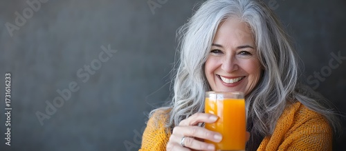An old woman drinking fresh orange juice for healthy, vitaminized nutrition in an active life