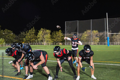 Tableau sur toile American football players practicing on a lighted stadium field at night, a quar