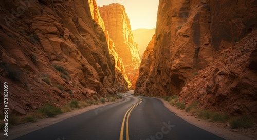 Scenic road winding through towering rock formations bathed in warm sunlight creating a dramatic landscape perspective