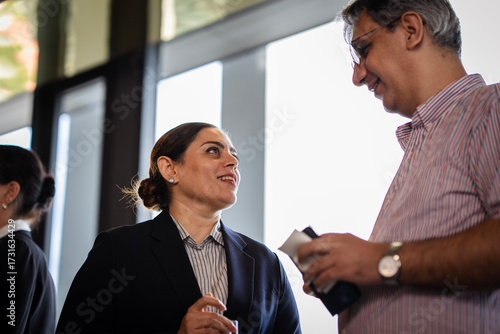 Colleagues enjoying networking conversation during a corporate event, representing workplace diversity, leadership, and informal team communication.