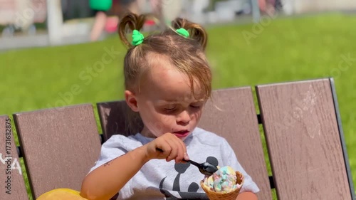 Little girl sitting on a bench holding an ice cream cone on a summer day