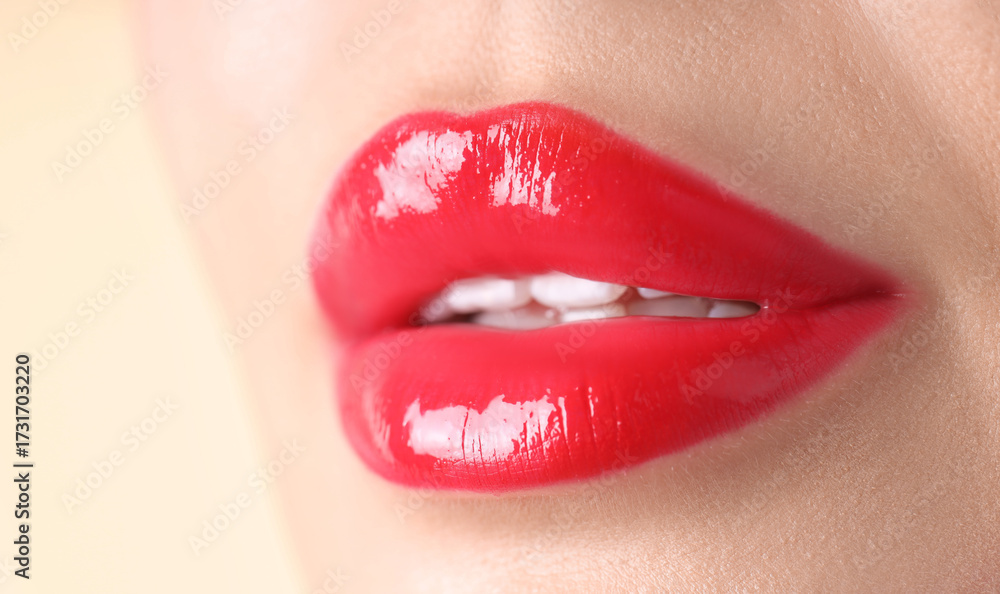 Obraz premium Woman with beautiful red lipstick on her lips against beige background, macro view
