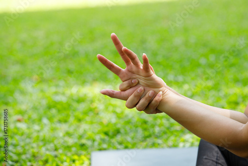 Close-up of a hand stretching exercise in the park. Gentle outdoor activity for joint flexibility, relaxation, and finger mobility in a green natural setting.