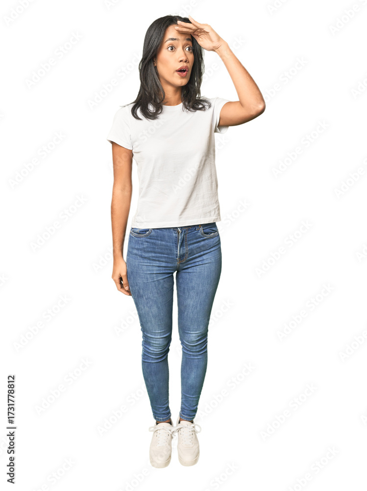 Fototapeta premium Full body shot of Latina in studio looking far away keeping hand on forehead.