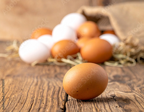 Farm fresh brown and white eggs piled in a burlap sack on a rustic wooden table, hinting at natural, wholesome food