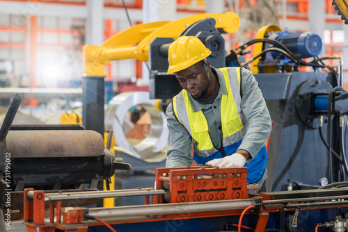 Engineers are working in a steel sheet factory. Technician in safety and helmet suit controlling a machine in factory.