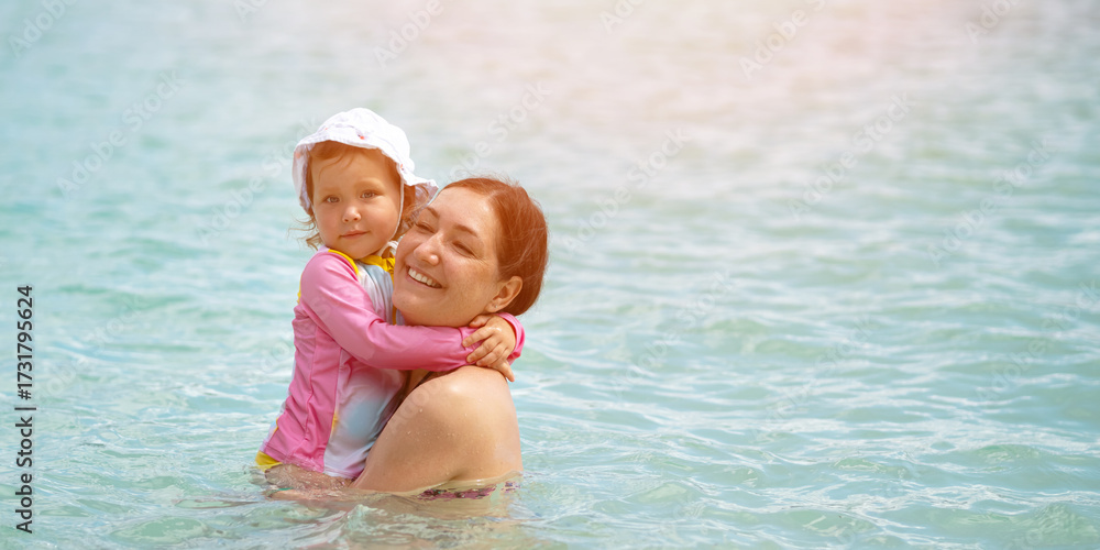 Fototapeta premium Mother and daughter embracing in tropical ocean water