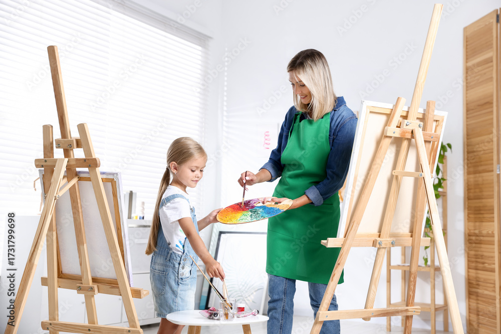 Naklejka premium Choice of profession. Mother teaching her daughter to paint in studio