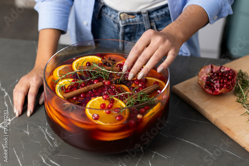 Making a festive punch with rosemary, cinnamon, oranges, and pomegranate for holiday celebrations