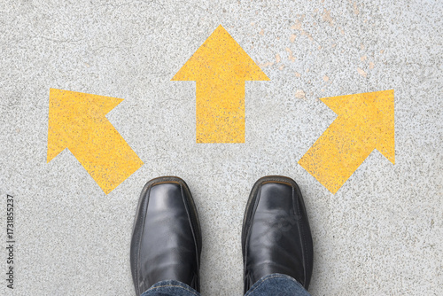 businessman standing at three direction arrows on concrete floor