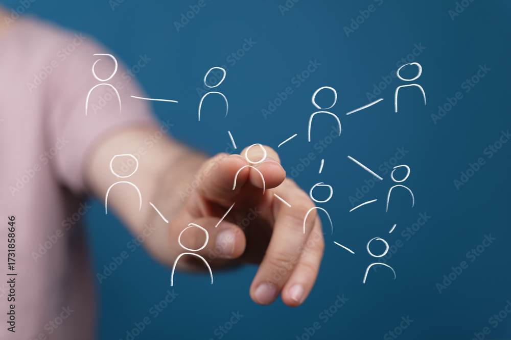 Fototapeta premium A human hand interacts with a digital network of interconnected user icons on a blue background, symbolizing social connection, global communica