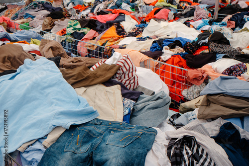 Photos piles of clothes stacked in bins at an outdoor market