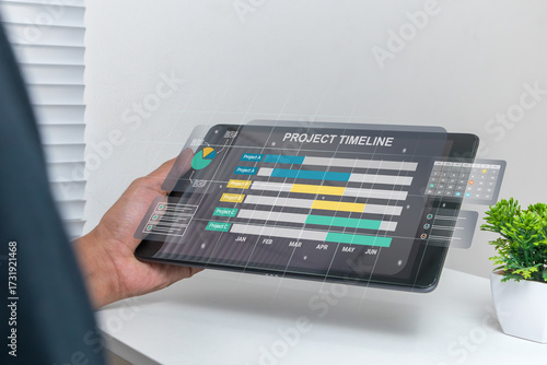 A man works on tablet computer to check project schedules, milestones, and planning progress to match the predetermined schedule