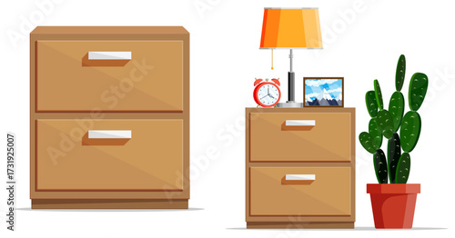 Wooden drawer set with lamp, alarm clock, picture, and potted cactus. Home furniture and decor concept.