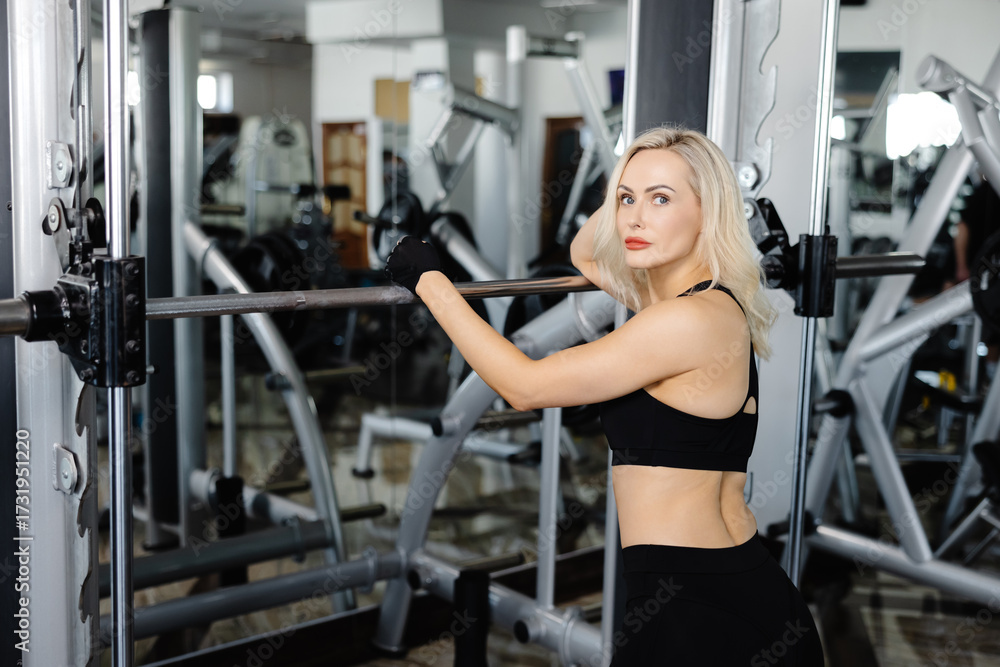 Obraz premium Athletic woman performing squats with barbell in gym