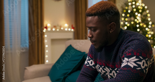 An upset young man sits on a couch. After a call with his boss, he learned he was fired, so he threw the phone aside and put his hand to his head in frustration.