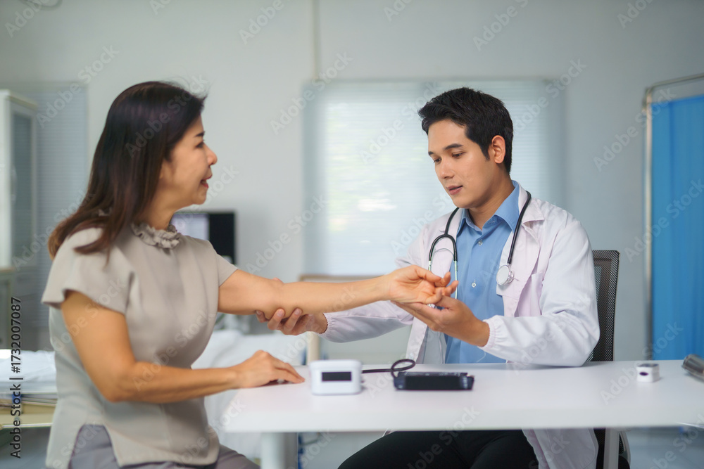 Fototapeta premium Doctor examining mature woman's arm in medical office