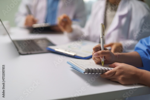 Medical team taking notes during meeting in hospital conference room