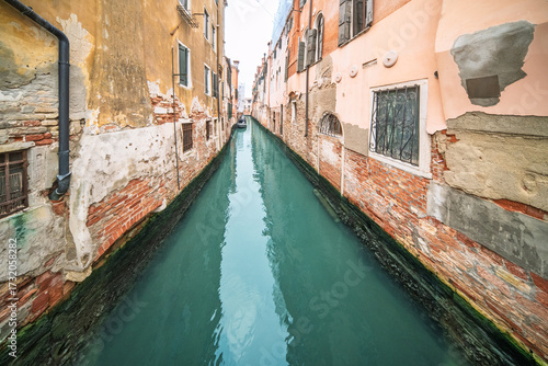 Narrow canal glimmering with turquoise water in Cannaregio, Venice