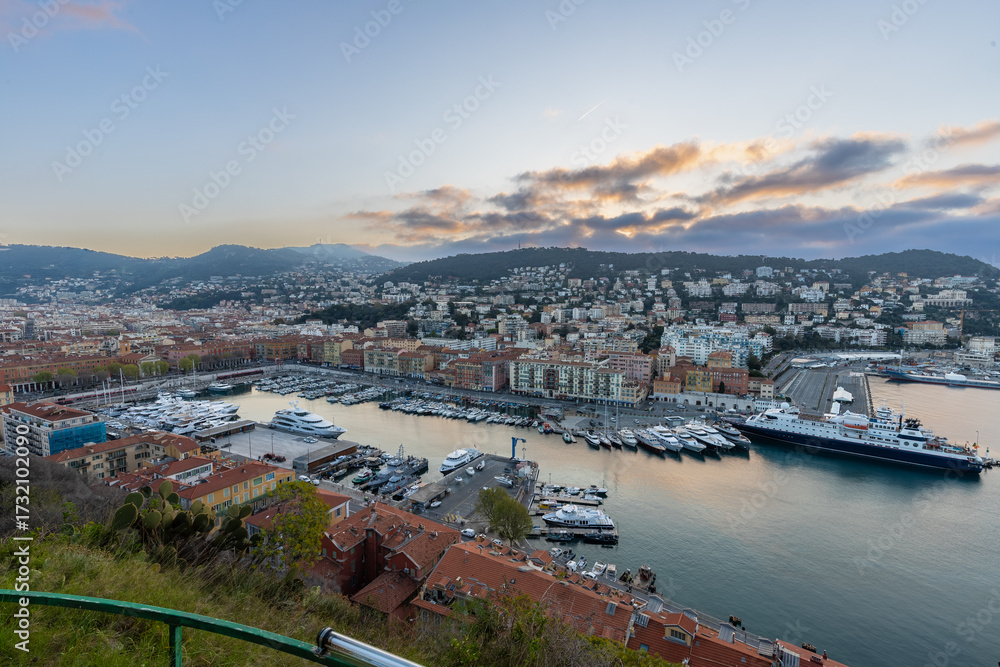 Fototapeta premium Sunrise just before golden hour starts in the harbour of Nice with luxury private boats and the beautiful houses on the shore. This is the place were the rich people meet.