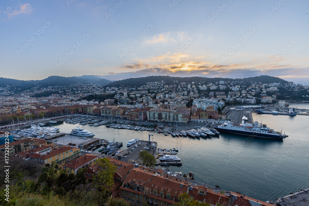 Obraz premium Sunrise just before golden hour starts in the harbour of Nice with luxury private boats and the beautiful houses on the shore. This is the place were the rich people meet.