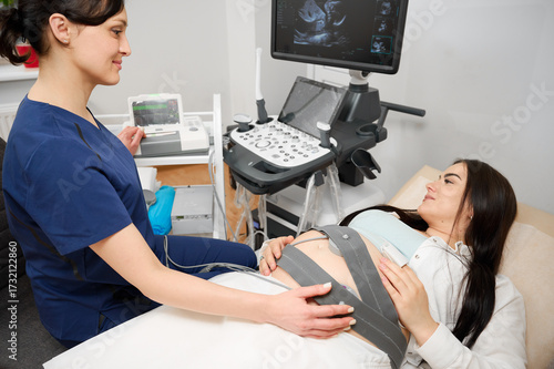 Pregnant woman undergoing cardiotocography procedure. CTG procedure to monitor fetal heartbeat and uterine contractions during pregnancy. A pregnant woman undergoes a medical examination.