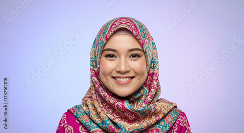Portrait of a smiling young woman wearing a colorful hijab, looking directly at the camera.