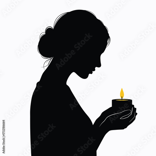Silhouette of a woman holding a lit candle in her hands contemplating light silhouette