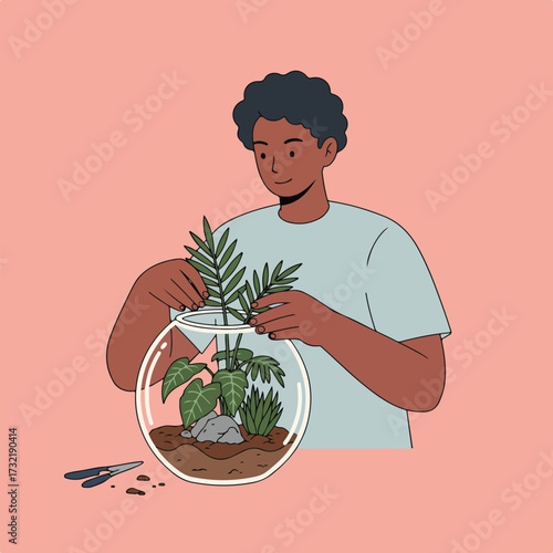 Person arranging plants in a glass terrarium against a coral background