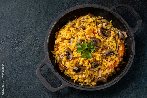Mushroom pilaf with rice in cast iron pan top view
