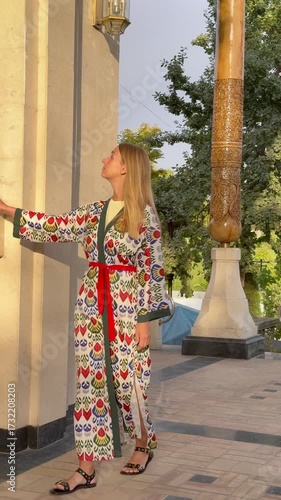 Woman in Uzbek patterned attire admiring traditional architecture in Tashkent