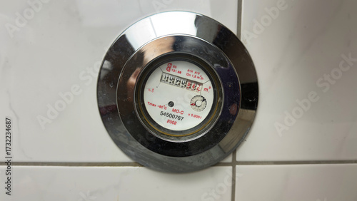 Close up of water meter dial with numbers and gauge showing water consumption measurement in plumbing system for monitoring utility usage, residential household billing and resource efficiency control