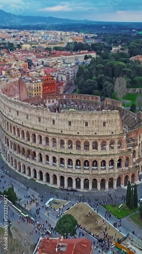 Establishing shot drone flying of the Colosseum. Famous Ancient Roman Arena. Downtown Rome, Italy. The Colosseum and the Imperial Forums in Rome. Beautiful aerial shot with drone around the Colosseum