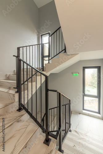 Modern stair case between floors. Stairs with metallic rail in modern building. Interior of a contemporary apartment or office building. Architecture and real estate background.