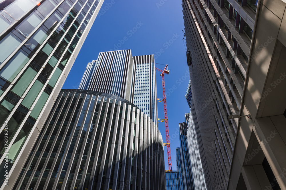 Naklejka premium Modern glass skyscrapers and red crane in business district, low angle urban view