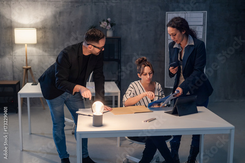 Business team working late in office analyzing documents under warm lamp light