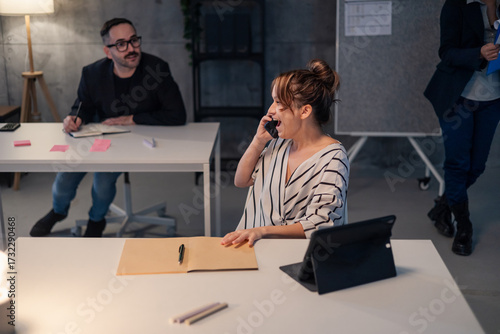 Businesswoman laughing while talking on phone in office at night