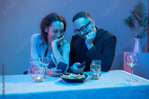 Couple enjoying smartphones during romantic dinner date