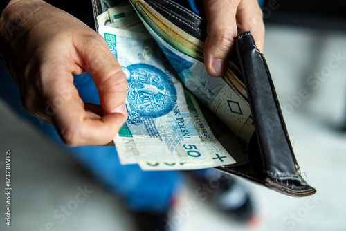 Tableau sur toile Person pulling out a 50 Polish zloty banknote from a leather wallet