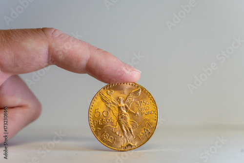 Foto Une pièce en or 50 pesos mexicain tenu debout par un doigt