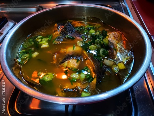 Silver catfish in yellow soup cooked in a stainless steel bowl.