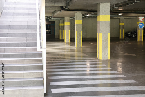 View of empty underground parking with dedicated spots, pedestrian crossing and stairs