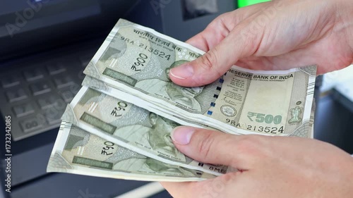 Close up view of woman hands counting Indian rupee banknotes (INR) in ATM. Concept of saving money for retirement, cash settlement, financial goals, success, literacy and income planning in India.
