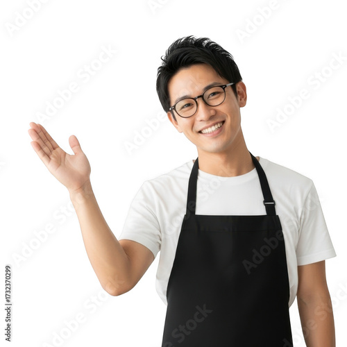 Smiling young man wearing glasses and an apron presenting with open hand isolated on transparent background