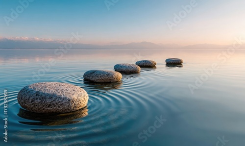 Stone path stepping across serene water with mountains & calm sky