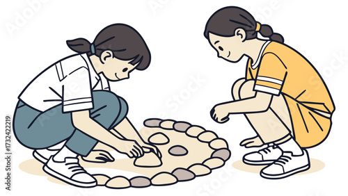 Two young girls crouch, carefully arranging stones into a circular pattern on the ground.